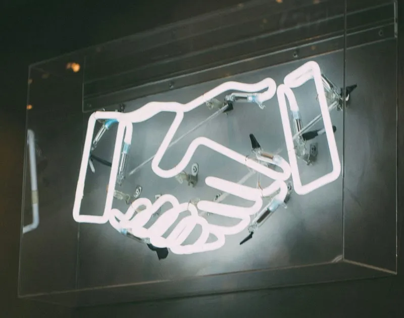 A neon sign of two hands shaking